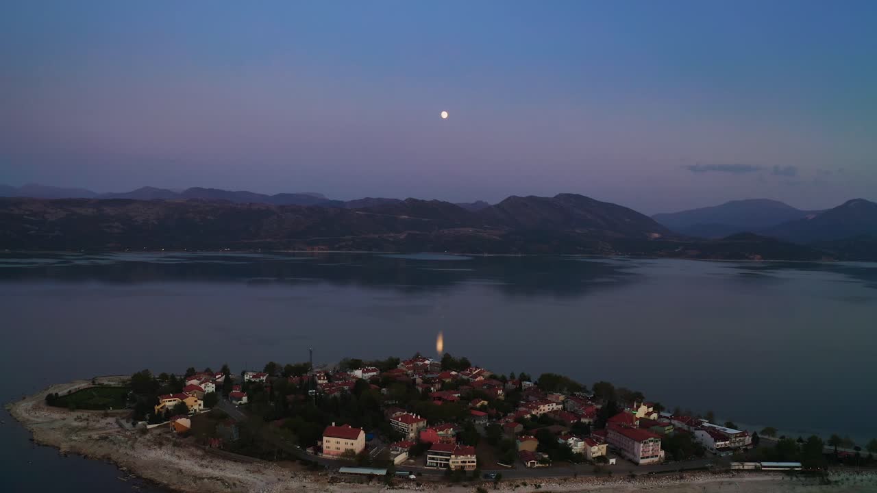 Luftfoto af en søby om natten med fuldmåne