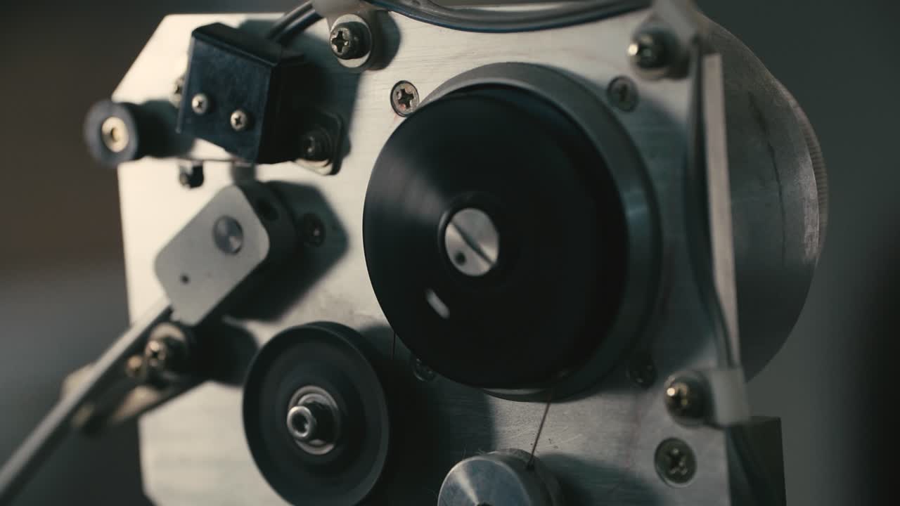 Close-up of a precision coil winding machine spinning fine copper wire onto a spool, showcasing detailed engineering, motion, and craftsmanship in speaker manufacturing