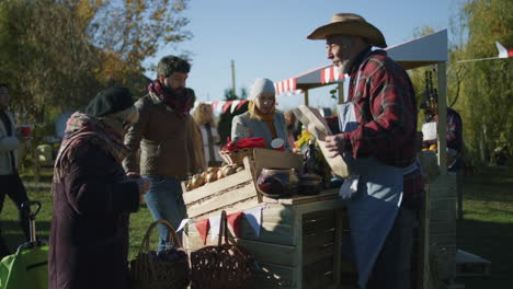 senior farmer selling products at autumn fair senior farmer selling fruits and vegetables at the stall elderly woman puts products in paper eco bag local farmers market or autumn fair outdoors agriculture point of sale system