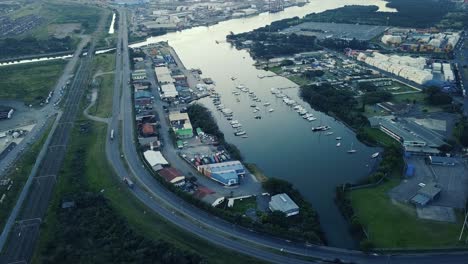 footage-of-sunset-overlooking-yachts-moored-with-traffic-on-a-road-and-shipping-containers-to-be-transported-to-ships-by-trucks