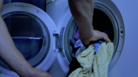 man´s arms taking clothes out of the washing machine