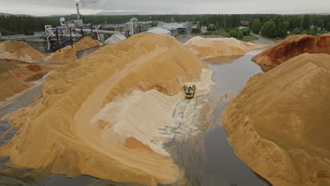 wheel dozer moving around mountains of sawdust at lumber mill, aerial