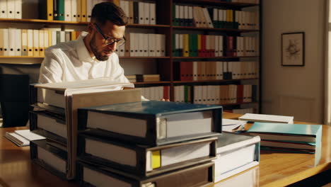 man working in a sunlit office with files