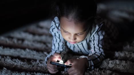 una chica joven usando un teléfono inteligente por la noche.