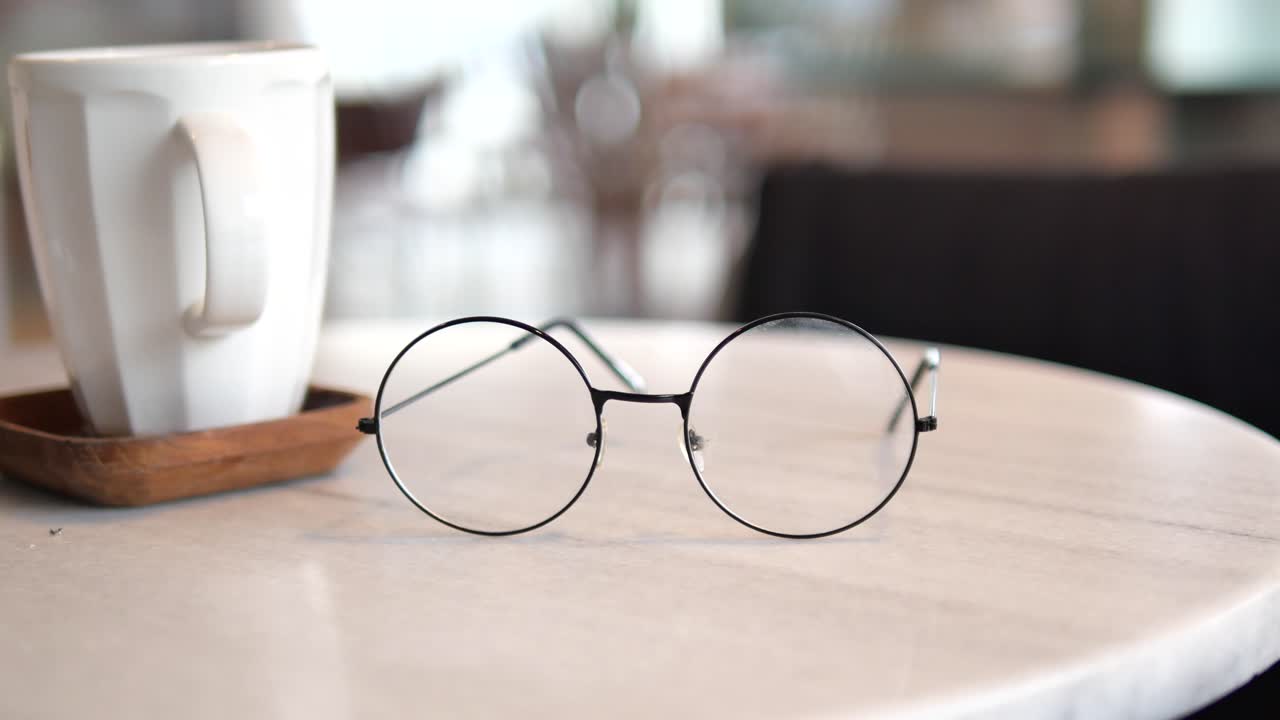 Round Glasses on a Marble Table Next to a Coffee Mug