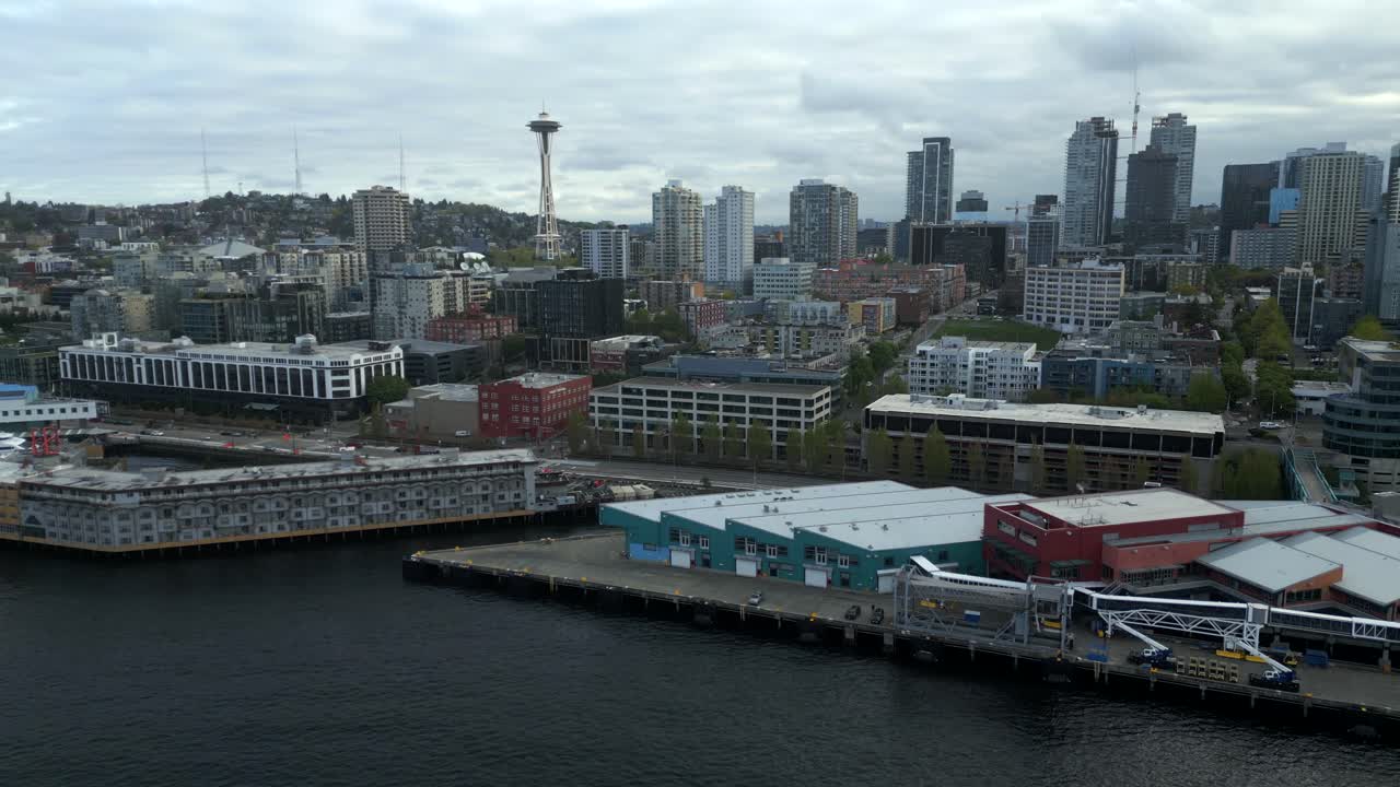 Scenic aerial drone shot of Pier 66 and The Edgewater Hotel along downtown Seattle Waterfront coastline with Space Needle in background - Washington, USA