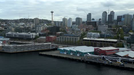 scenic aerial drone shot of pier 66 and the edgewater hotel along downtown seattle waterfront coastline with space needle in background - washington, usa