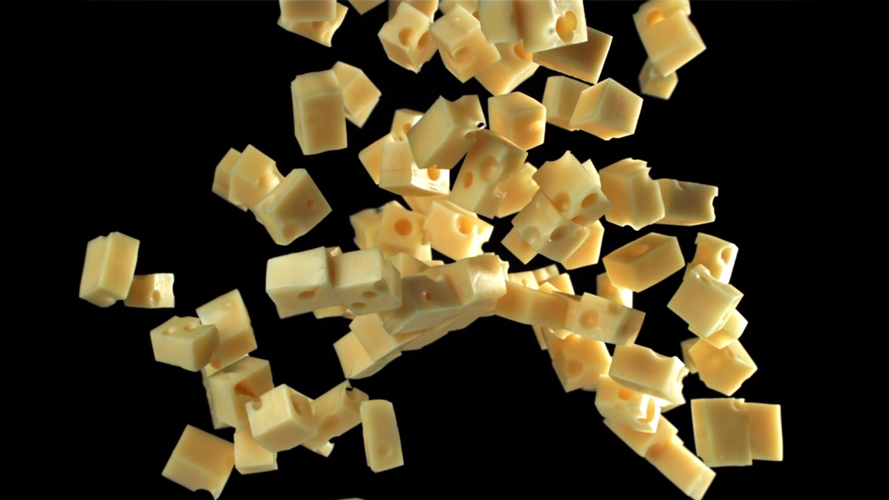 Yellow Cheese Cubes with Holes Falling in Slow Motion on Black Background