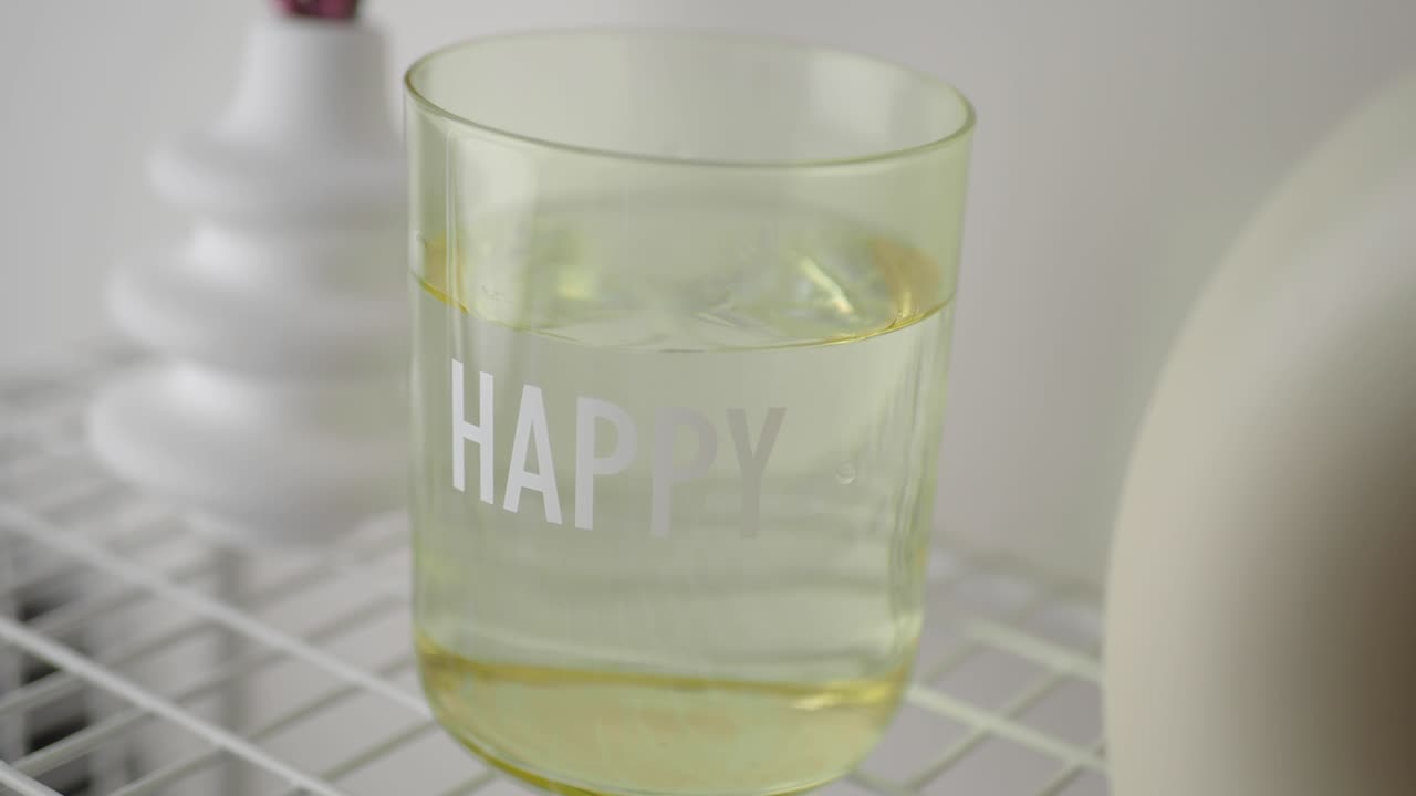 A glass with the word "HAPPY" on it filled with water