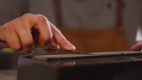 hand sharpens special cutter with sandpaper in craft shop