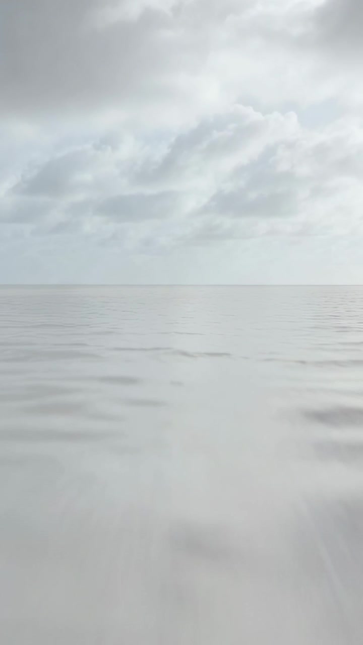 Vertical video: Showing calm sea and cloud band shifting as time passes at sea, with sun reflection
