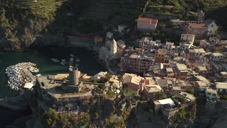 Droneshot-Adelante-Con-Cierta-Inclinación-Hacia-El-Pueblo-De-La-Costa-Italiana-Con-Un-Tren-Que-Pasa-Verdadero-Al-Amanecer-4k