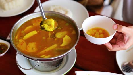 ladling soup into a bowl at a table