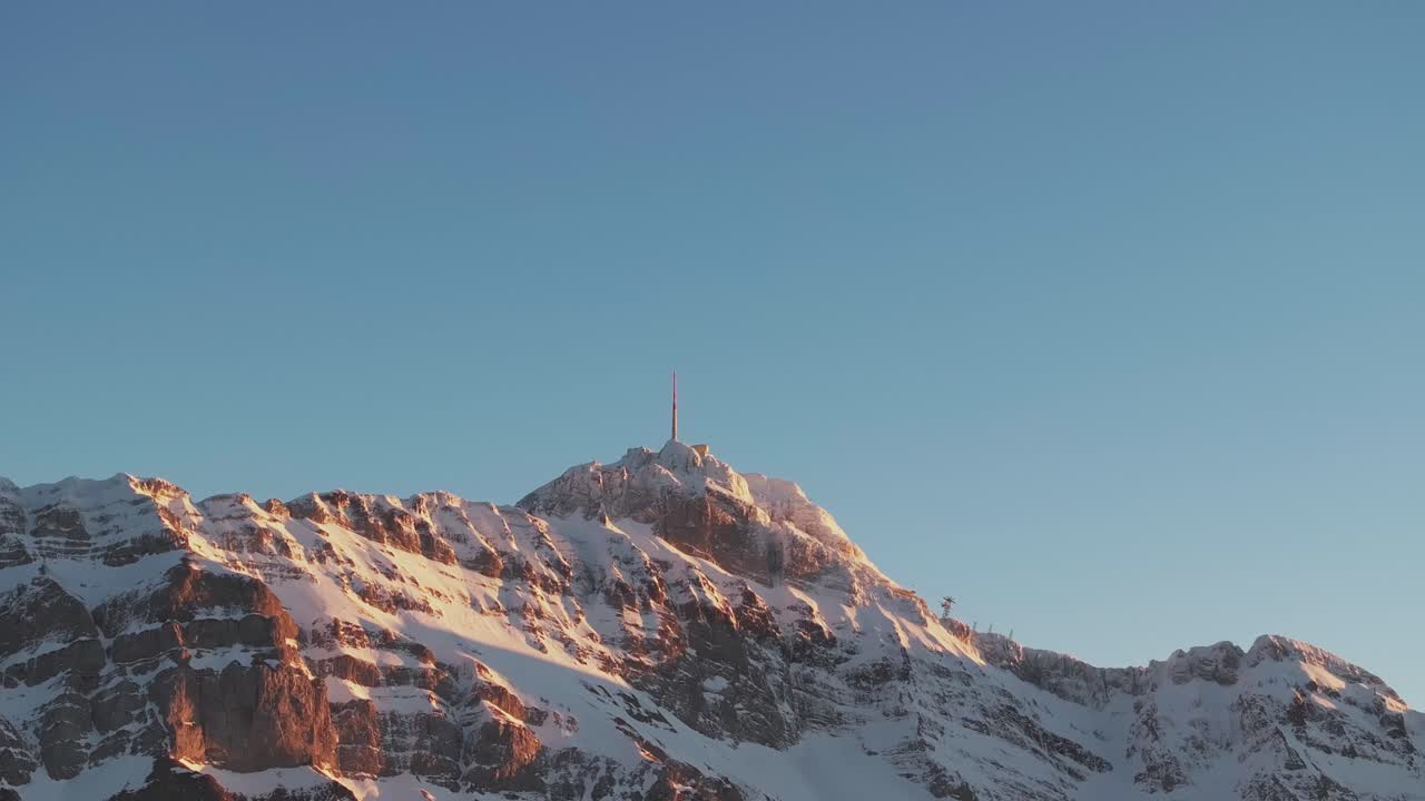 завораживающий кадр с беспилотника, показывающий силуэт заснеженного горного хребта во время восхода солнца