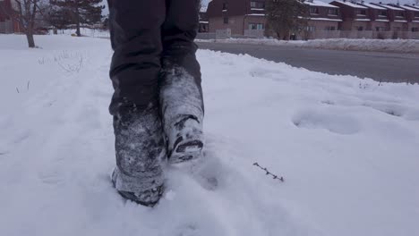 Child-walking-in-snow-wearing-snow-pants,-snow-boots,-gloves-in-urban-area-in-winter