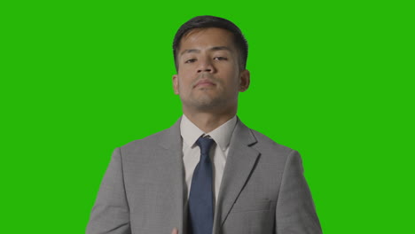 portrait of serious businessman doing up suit jacket against green screen looking at camera 1