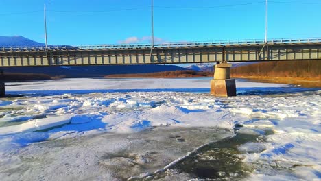 volando un dron sobre bloques de hielo bajo un puente 4k