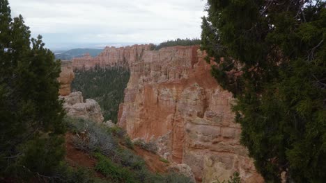 Tilt-down-shot-revealing-a-beautiful-southern-Utah-desert-valley-landscape-with-large-hoodoo-formations-from-erosion-surrounded-by-greenery-on-an-overcast-spring-day