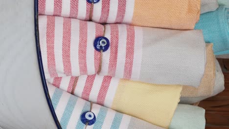 stack of colorful striped towels with evil eye beads