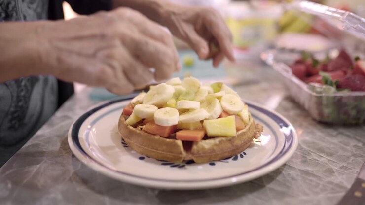 mujer preparando gofres dulces con frutas para el desayuno