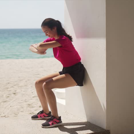 Young-woman-doing-wall-squats-on-beach