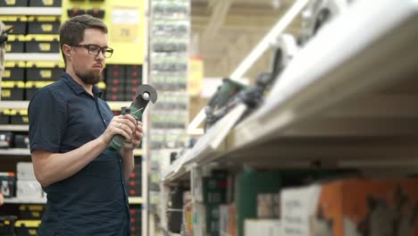 man looking at power tool in hardware store