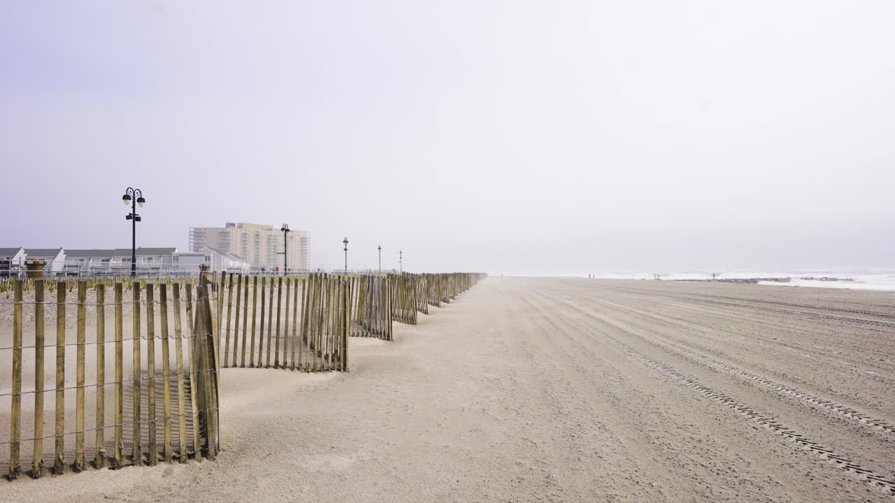 Clean beach on a warm sunny morning with people on boardwalk passing by in OCNJ