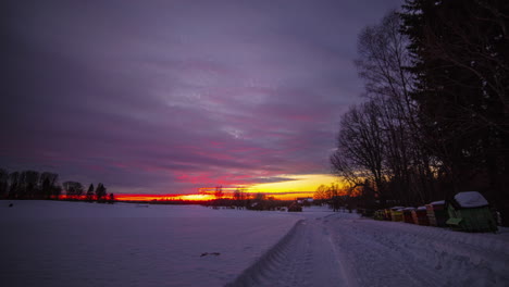 snowy, winter landscape and the orange sun on the horizon, with the clouds advancing