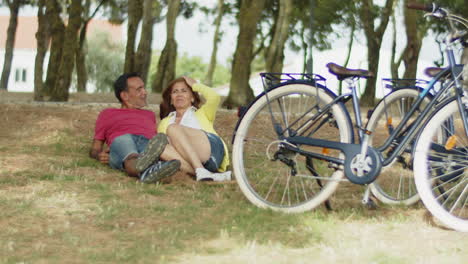 front view of happy senior couple lying on grass in park