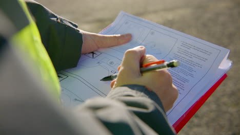 engineer reading and analyzing schematics on the clipboard while holding a pen, handheld closeup