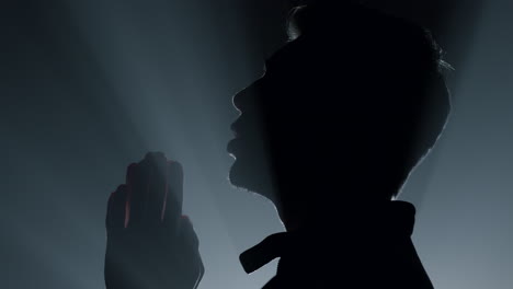 어 ⁇ 에서 기도하는 실루 ⁇  남자. 실내에서 기도를 속삭이는 남성.