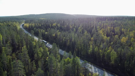 Bus-and-car-drive-on-highway-through-rolling-autumn-boreal-forest