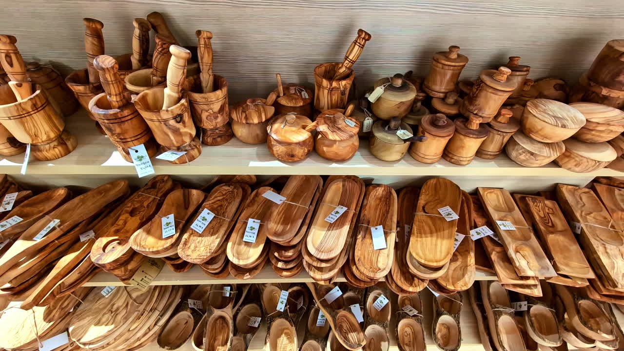 Olivewood hand carved into bowls, platters, and other souvenirs at a Greek market - panning reveal