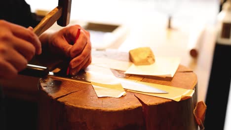 hands expertly slicing cheese on a wooden board