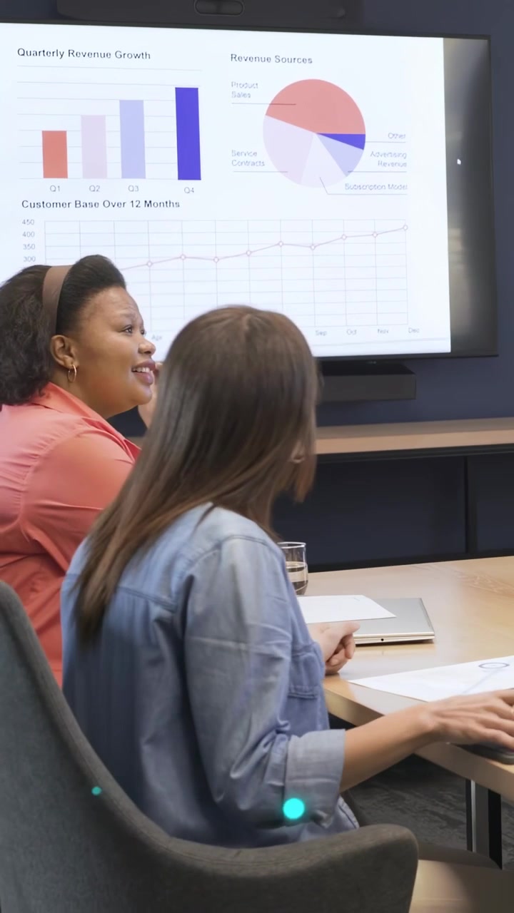 Vertical video: Woman at laptop starting slide causing blue overlay on revenue charts for review