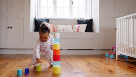 female toddler at home playing with stacking plastic toy