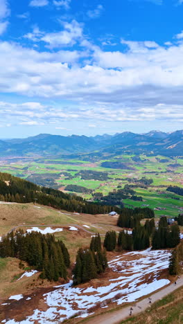 vast mountainous landscape with some snow covering the area. funicular road is on the mountain top. scenery of bavarian nature, germany. vertical video.