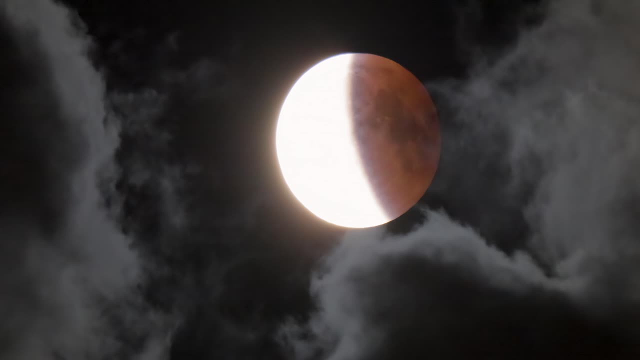 Lunar eclipse. The moon on the background of a dark sky with clouds