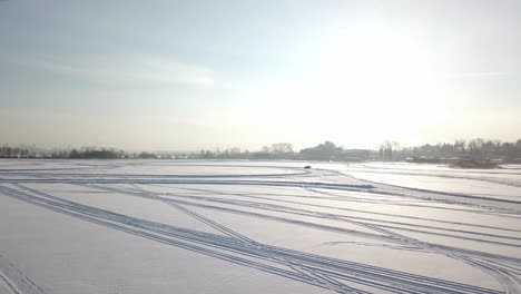 aerial view of a car driving on a frozen lake in winter