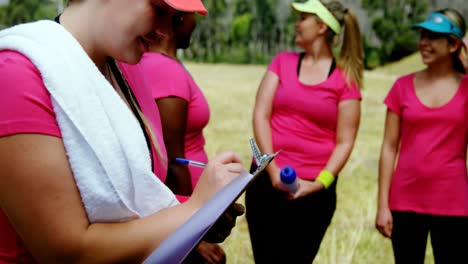 Entrenadora-Escribiendo-En-El-Portapapeles-En-El-Campo-De-Entrenamiento