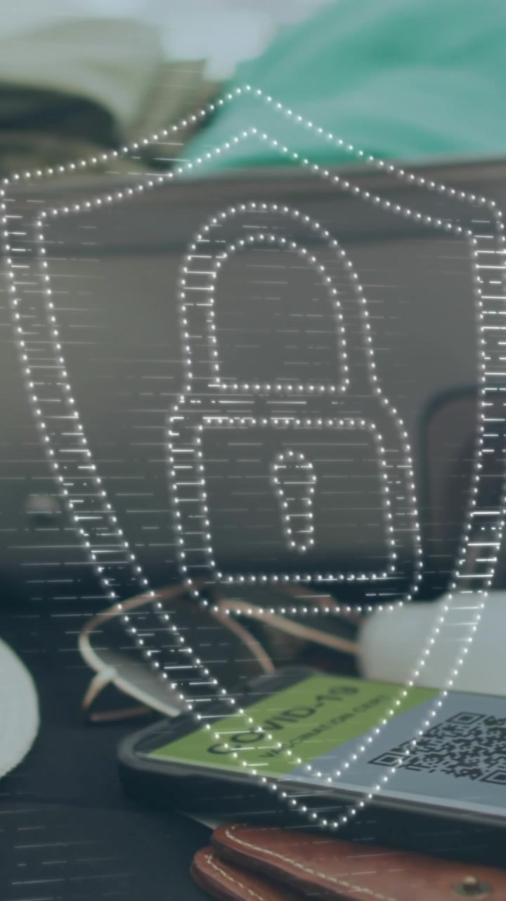Animation of digital padlock and shield over smartphone with qr code, luggage, hat and mask on bed