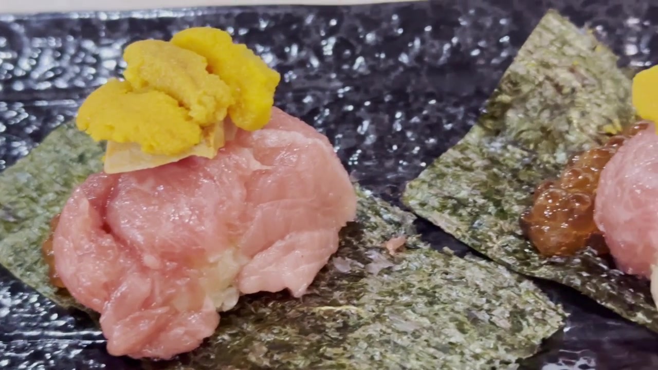 Cận cảnh cuộn otoro cầm tay được cuộn trong rong biển, phủ gan ngỗng cao cấp và nhím biển tươi, thể hiện trải nghiệm ẩm thực Nhật Bản sang trọng, tinh tế