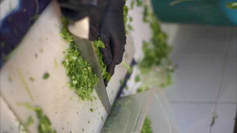 Cierre-Vertical-En-Cámara-Lenta-De-Un-Cocinero-Hispano-Latino-Con-Guantes-De-Látex-Negros-Cortando-Cilantro-Con-Un-Cuchillo-Grande-En-Un-Restaurante-En-México