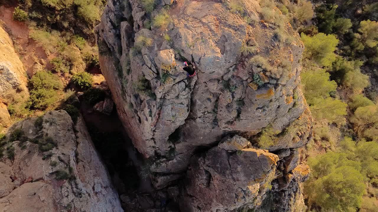 Luftaufnahme eines Mannes beim Felsklettern und eines Sportlers beim Abseilen am Berg in La Panocha, El Valle Murcia, Spanien, mit einer Frau, die sich einen Berg hinabseilt und einen großen Felsen erklimmt.