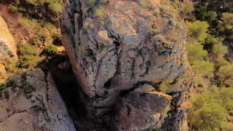 Man-rock-climbing-aerial-view-of-sportsman-rapelling-mountain-in-La-Panocha,-el-Valle-Murcia,-Spain-woman-rapel-down-a-mountain-climbing-a-big-rock