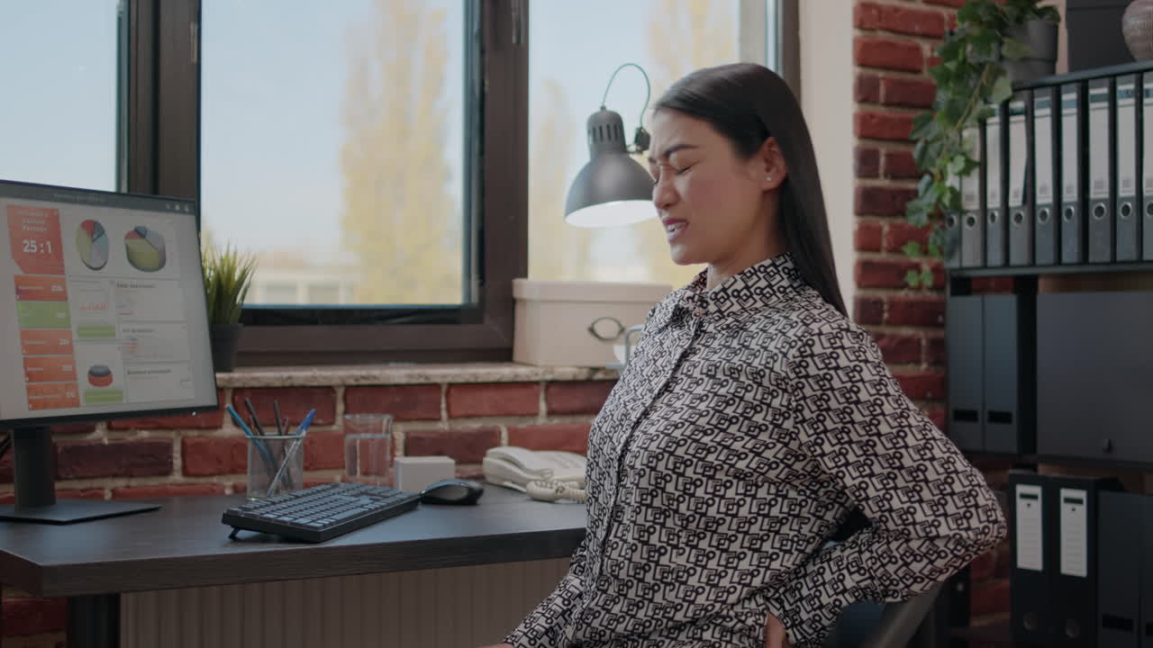 Business woman suffering from back pain and working on computer