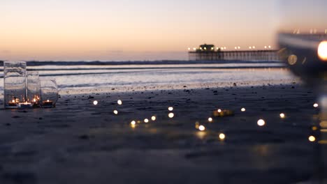 candle flame lights in glass, romantic beach date by ocean waves, summer sea. candlelight on sand.