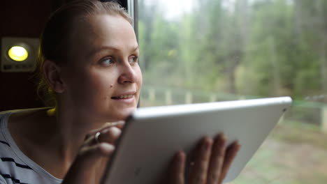 Mujer-Joven-Usando-Un-Panel-Táctil-Sentada-Junto-A-La-Ventana-En-El-Tren