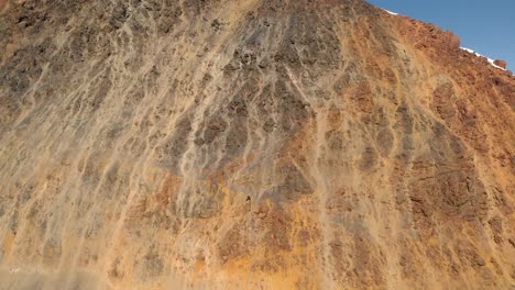 Aerial-reveal-shot-of-Mount-Ushba,-Georgia,-starting-with-a-view-of-a-rocky-wall-in-front-of-the-mountains