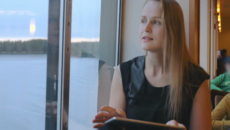 Woman-Sitting-Near-The-Window-And-Using-Tablet